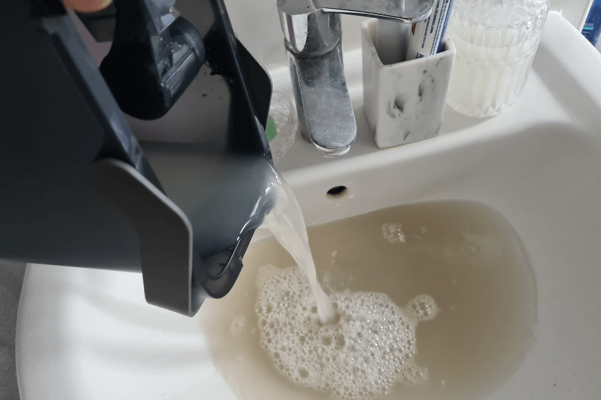 The dirty water after cleaning by Roborock S7 MaxV Ultra is tipped into the sink.